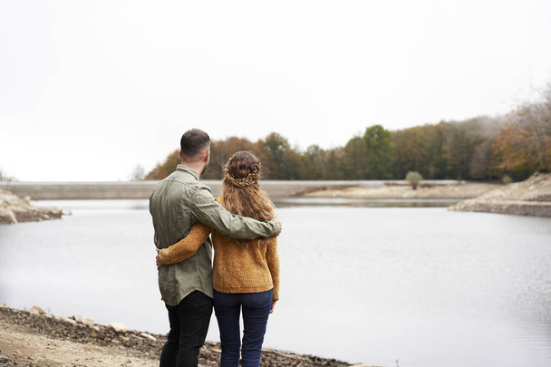 湖で抱き合っている素敵な若いカップルのバックビュー. - 写真・画像