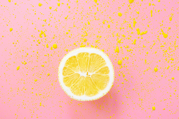 Metade de limão em um fundo rosa. Manchas de tinta amarela à volta. Conceito de citrinos de verão brilhante. - Foto, Imagem