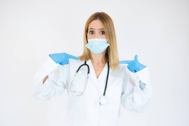 Mooie vrouwelijke arts of verpleegkundige dragen beschermende masker en latex of rubber handschoenen op witte achtergrond met kopieerruimte. Gezondheidszorgconcept - Foto, afbeelding