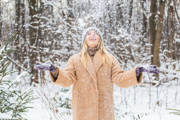Młoda kobieta rzuca śnieg w powietrze w słoneczny zimowy dzień, jest szczęśliwa i zabawna. - Zdjęcie, obraz