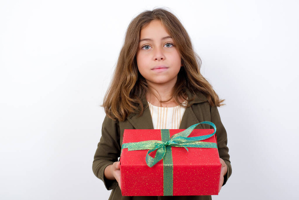 schönes kleines Mädchen in grünem Mantel mit Geschenk auf weißem Hintergrund  - Foto, Bild