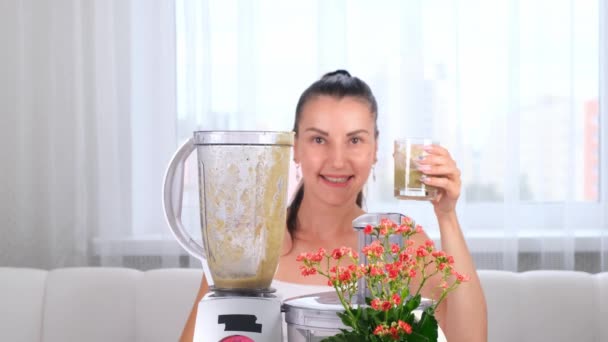 szczęśliwa młoda kobieta przygotowuje pyszne odżywcze smoothie w kiwi blender - Materiał filmowy, wideo