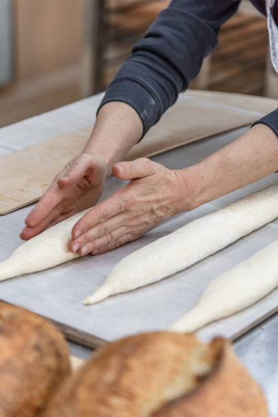 Making craft bread at the bakery. Close-up of a baker and bread, blurred background - 写真・画像