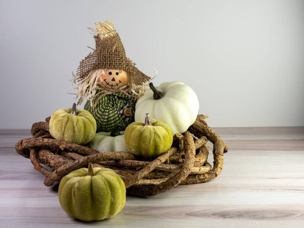 Épouvantail avec tenue verte et chapeau en toile de jute assis sur une couronne de bois avec de petites gourdes vertes l'entourant pour un décor d'automne, parfait pour l'automne et l'Halloween. - Photo, image