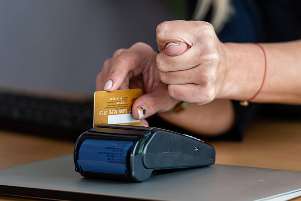 woman using payment card terminal to shop online with credit card and shows a fig with his other hand, the concept of denial of online fraud - Photo, Image