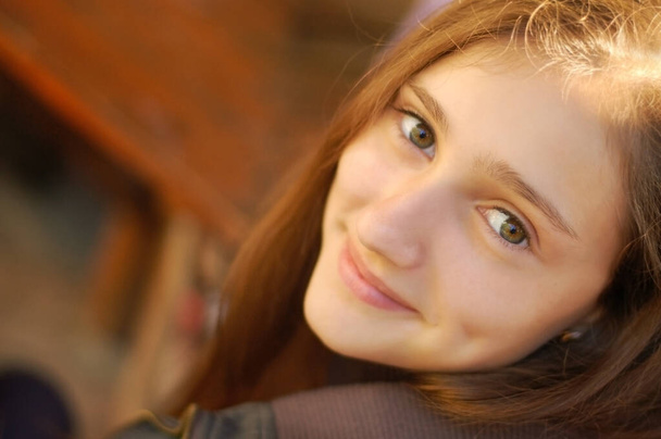 Ritratto di una giovane ragazza carina che si siede in un parco su una panchina al tramonto. Sorride. - Foto, immagini