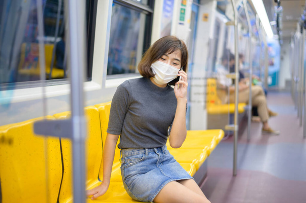 A young woman is wearing protective mask in metro , covid-19 protection , safety travel , new normal , social distancing , safety transportation , travel under pandemic concept . - Foto, imagen