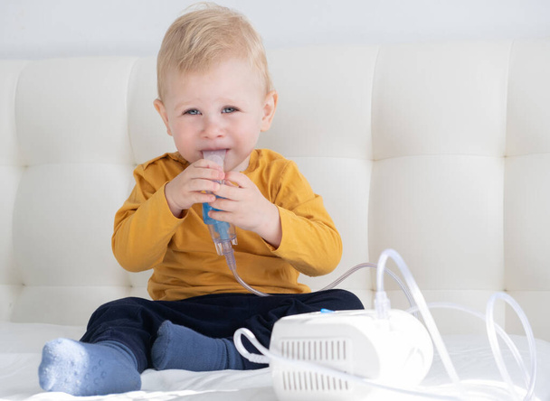 Little baby boy using steam inhaler nebulizer himself on the bed. copy space. health medical care. - Photo, Image