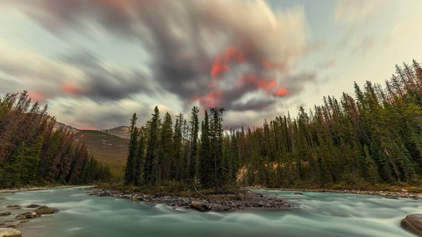 美しい赤い雲は、カナダのアルバータ州ジャスパー国立公園のSunwapta滝の近くにあるSunwapta川をひっくり返しました。. - 写真・画像