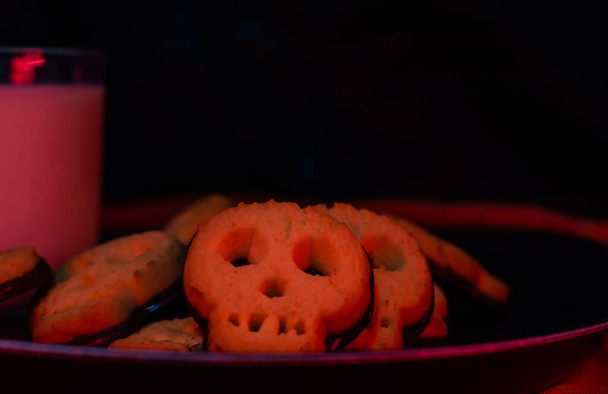 Печенье с черепом на Хэллоуин со стаканом молока - пространство для копирования черного фона - настроение ужаса - Фото, изображение