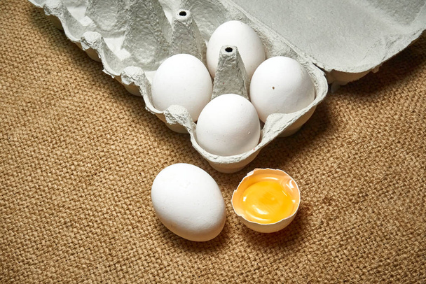 Fresh raw chicken eggs in a cardboard box on a burlap background - Photo, Image