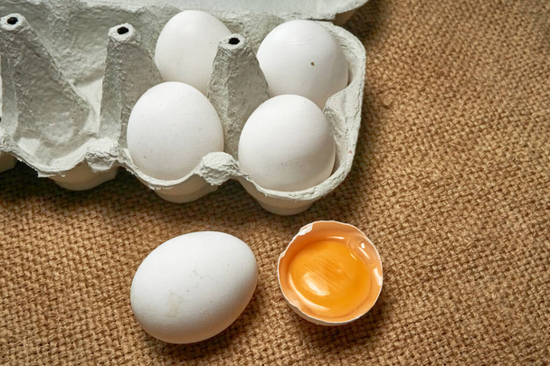Huevos de pollo crudos frescos en una caja de cartón sobre un fondo de arpillera - Foto, imagen
