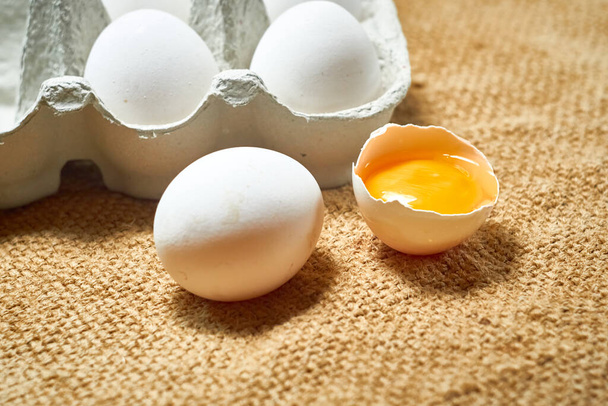 Uova di pollo crude fresche in una scatola di cartone su uno sfondo di iuta - Foto, immagini
