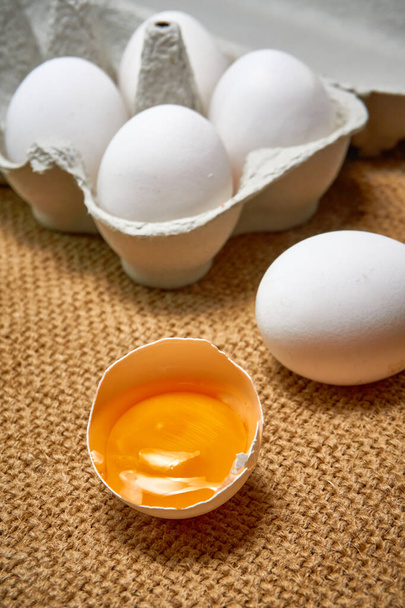 Tuoreet raa 'at kananmunat pahvilaatikossa säkkikangastaustalla - Valokuva, kuva