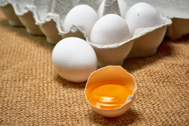 Tuoreet raa 'at kananmunat pahvilaatikossa säkkikangastaustalla - Valokuva, kuva