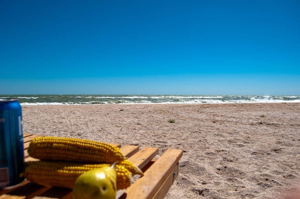 kukuřičné palice s hruškami na dřevěné lavičce u moře - Fotografie, Obrázek