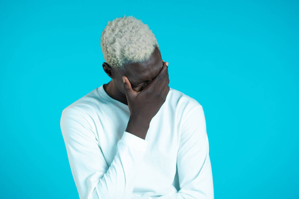 Portrait of young african man doing facepalm gesture, like no, I forgot. Unhappy black guy feeling sorrow, regret, drama, failure. He isolated on blue wall - Φωτογραφία, εικόνα
