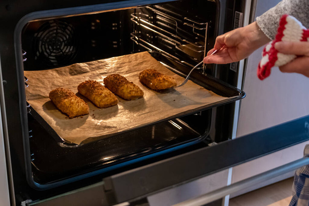vrouw het nemen van gebakken koekjes uit elektrische oven - Foto, afbeelding