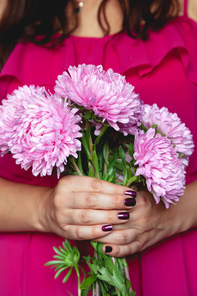 girl in a red dress holding a bouquet of pink chrysanthemum - Foto, Imagen
