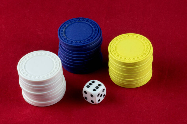Farbige Glücksspielchips und weiße Würfel auf rotem Hintergrund - Foto, Bild