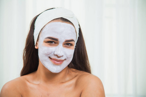 Portrait of a young fresh female face in facial white clay mask. - Photo, Image