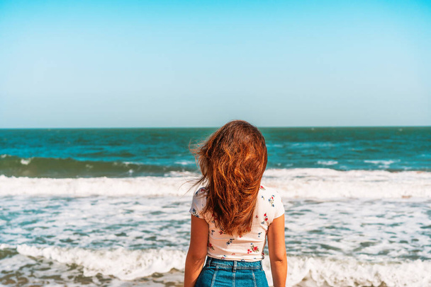 Schöne junge Frau mit langen Haaren spaziert am Strand am Schwarzen Meer entlang - Foto, Bild
