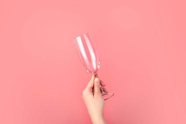 Рука держит бокал шампанского на розовом фоне. - Фото, изображение