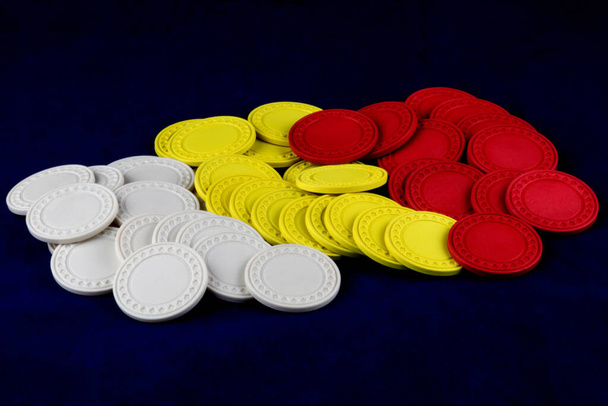 Piled kolorowe żetony hazardowe izolowane na niebieskim tle - Zdjęcie, obraz