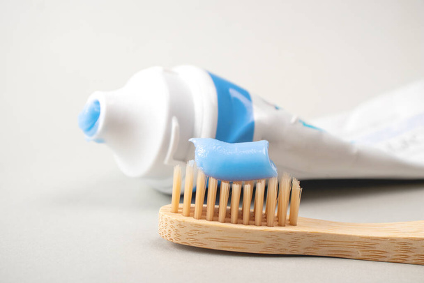 Milieuvriendelijke Bamboe tandenborstel en plak op een grijze achtergrond. Orale zorg concept. Toebehoren voor ecologische gezondheid. - Foto, afbeelding