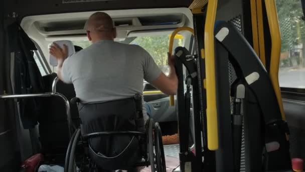 Hombre en silla de ruedas en el especial del vehículo. La persona con discapacidad es transportada en un coche especial. Transporte de personas con discapacidad en un coche especial, autobús. - Metraje, vídeo