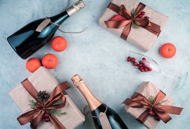 Szczęśliwego Nowego Roku i Wesołych Świąt, prezenty, butelka alkoholu, mandarynki i kieliszki do wina na jasnym tle. - Zdjęcie, obraz