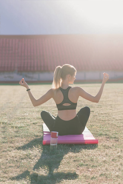 Jonge vrouw alleen in het stadion doet yoga - Foto, afbeelding