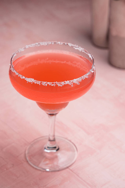 Red Margarita cocktail and some bartender accessories on a pink background - Foto, afbeelding