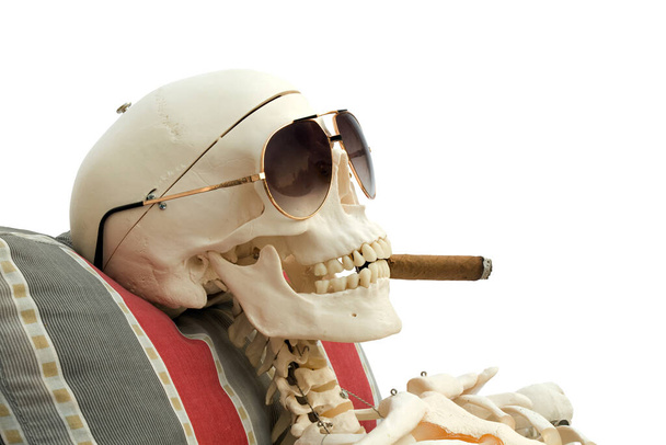 Scheletro con sigaro sulla sedia a sdraio. Fumare uccide. - Foto, immagini