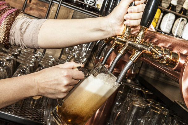 Een biertje in een mok gieten uit de kraan. In een pub. - Foto, afbeelding