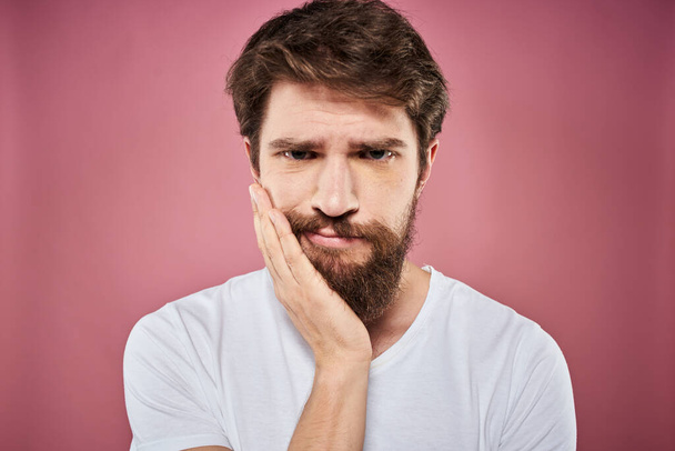 γενειοφόρος άνδρας σε λευκό t-shirt συναισθήματα δυσαρέσκεια προσώπου έκφραση στούντιο ροζ φόντο - Φωτογραφία, εικόνα