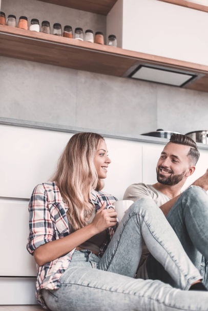 young couple drinking coffee sitting on the kitchen floor - Foto, Imagem
