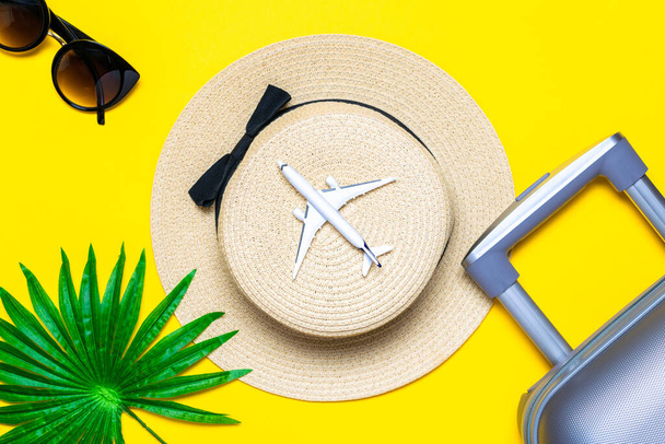 Merhaba yaz. Kadın aksesuar gezgini: bavul, beyaz uçak, sarı arka planda güneş gözlüğü ve mesaj için boş alan. Kopyalama alanı olan sakin sahil sahnesi - Fotoğraf, Görsel