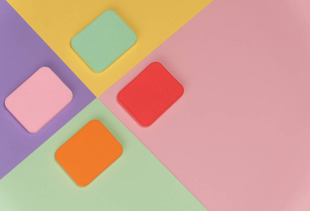 Top view of multi-colored sponges on different pastel-colored background. Абстрактное изображение. - Фото, изображение
