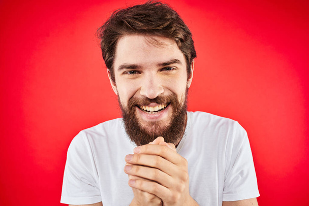 Bärtiger Mann Spaß Emotionen Lifestyle beschnitten Ansicht weißes T-Shirt roter Hintergrund - Foto, Bild