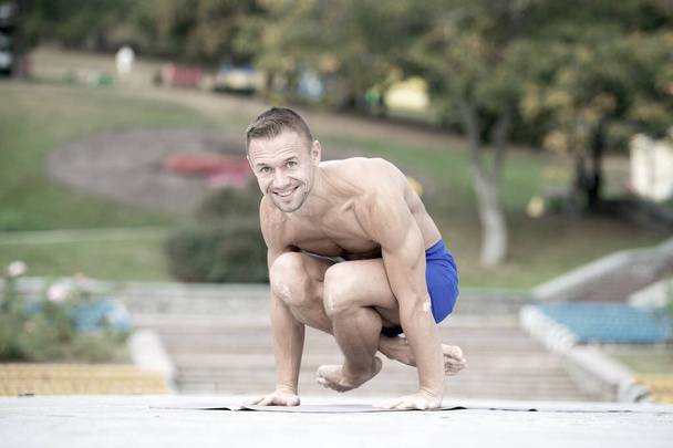Athletic man doing yoga asanas in the park - Photo, image