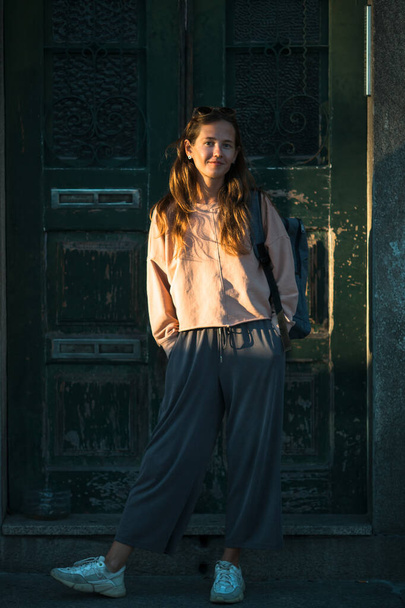 A young woman poses against the background of the old doors of the house. - Фото, изображение