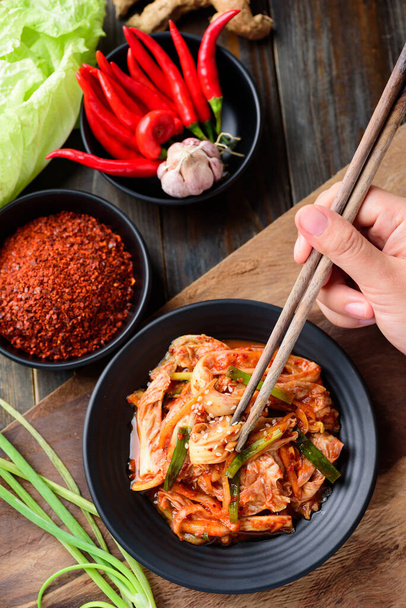 Korean food, Kimchi cabbage on plate eating with chopsticks on wooden background - Foto, Imagem