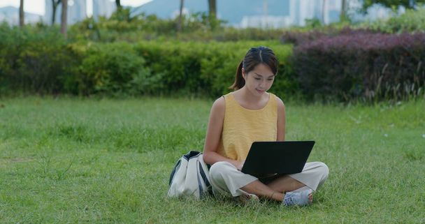 Mulher trabalhar no computador portátil e sentar-se no gramado verde - Foto, Imagem