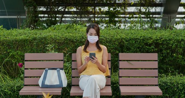 Woman wears face mask and uses mobile phone - Φωτογραφία, εικόνα