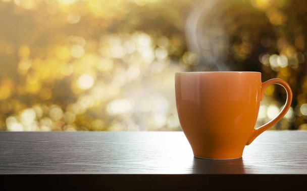 Una taza de café caliente en la mesa. Concepto de relajación. Vista lateral. Bokeh dorado como fondo - Foto, imagen
