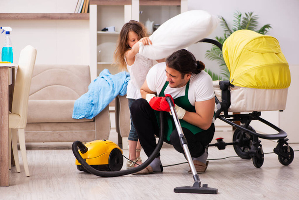 Young male contractor cleaning the house with his small daughter - 写真・画像