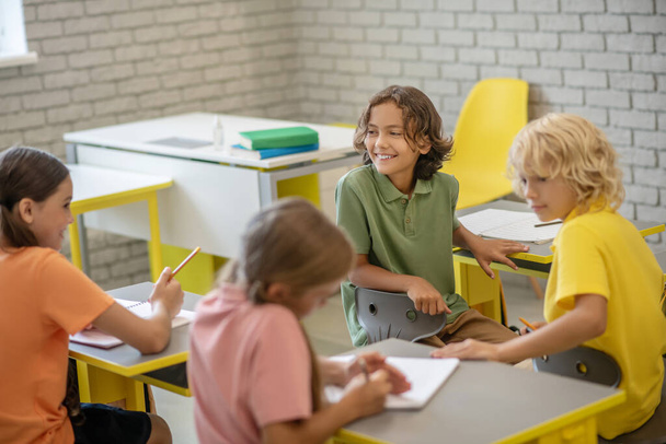 Children sitting at the desks in the classroom and looking contented - Фото, зображення