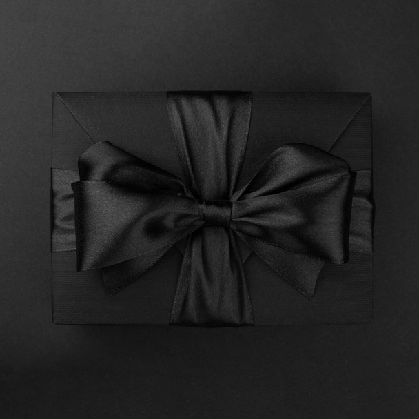 Black friday sale box gift present with ribbon bow on black conceptual design - Фото, изображение