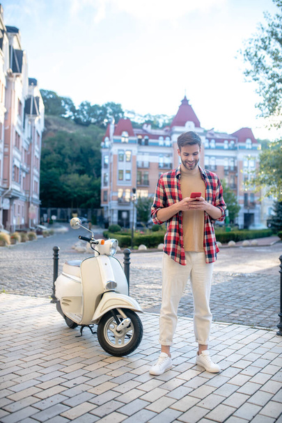 Man having a white scooter texting with his girlfriend - Zdjęcie, obraz